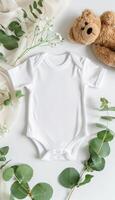 Baby bodysuit mockup with teddy bear and eucalyptus branch on ivory blanket, infant onesie template photo