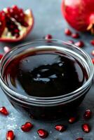 Pomegranate molasses and sour sauce with fresh ripe pomegranate fruit on a table setting photo