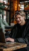 alegre joven hombre con un sonrisa utilizando un ordenador portátil en un cómodo hogar oficina ambiente foto