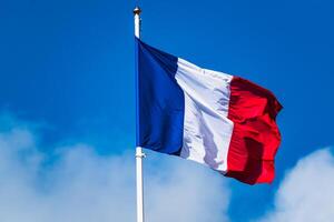 francés tricolor bandera revoloteando con fuerte viento y azul cielo foto