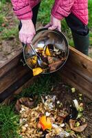 Person who put in a composter some kitchen waste like vegetables, fruits, eggshell, coffee grounds in order to sort and make bio fertilizer photo