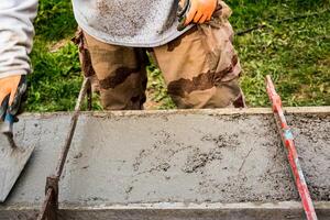 Bricklayer spreading concrete with a trowel and level to build a wall at a construction site photo