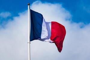 francés tricolor bandera revoloteando con fuerte viento y azul cielo foto