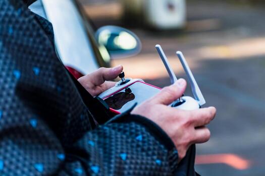 Man piloting a drone using a controller equipped with a joystick and a mobile screen photo