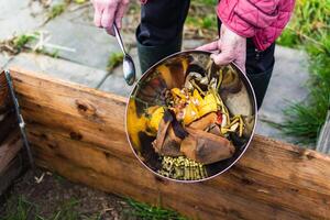 persona quien poner en un compostador algunos cocina residuos me gusta verduras, frutas, cáscara de huevo, café jardines en orden a ordenar y hacer bio fertilizante foto