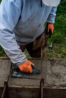 Bricklayer spreading concrete with a trowel and level to build a wall at a construction site photo