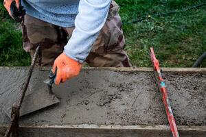 Bricklayer spreading concrete with a trowel and level to build a wall at a construction site photo