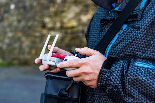 Man piloting a drone using a controller equipped with a joystick and a mobile screen photo