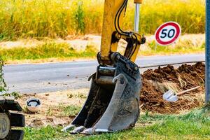 Arm of a mini digger and bucket with a speed limit sign at 50, road sign photo