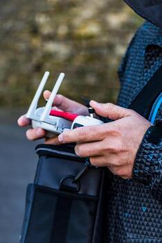 Man piloting a drone using a controller equipped with a joystick and a mobile screen photo