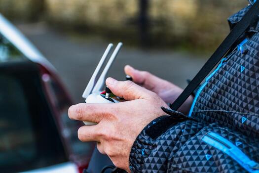 Man piloting a drone using a controller equipped with a joystick and a mobile screen photo