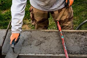 Bricklayer spreading concrete with a trowel and level to build a wall at a construction site photo