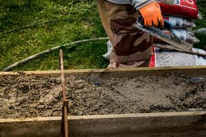 Bricklayer spreading concrete with a trowel and level to build a wall at a construction site photo