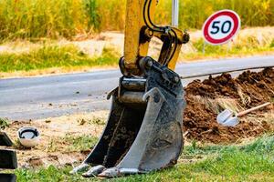 Arm of a mini digger and bucket with a speed limit sign at 50, road sign photo