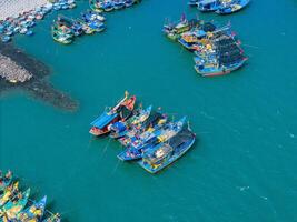 aéreo ver de loc un pescar aldea, vung tau ciudad. un pescar Puerto con tsunami proteccion hormigón bloques paisaje urbano y tradicional barcos en el mar. foto