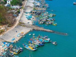 aéreo ver de loc un pescar aldea, vung tau ciudad. un pescar Puerto con tsunami proteccion hormigón bloques paisaje urbano y tradicional barcos en el mar. foto