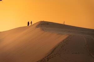 Aerial view of a peasant woman carries a bamboo frame on the shoulder across sand dunes in Ninh Thuan province, Vietnam. It is one of the most beautiful places in Vietnam photo