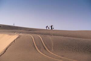 Aerial view of a peasant woman carries a bamboo frame on the shoulder across sand dunes in Ninh Thuan province, Vietnam. It is one of the most beautiful places in Vietnam photo