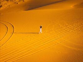 Aerial view of Vietnamese woman wearing ao dai dress across sand dunes in Ninh Thuan province, Vietnam. It is one of the most beautiful places in Vietnam photo