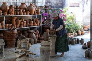 a pottery artist create traditional handicraft clay vase in Bau Truc pottery village. Using traditional techniques. photo