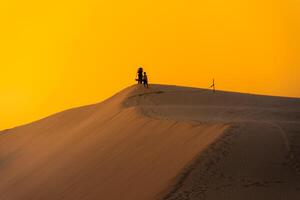 Aerial view of a peasant woman carries a bamboo frame on the shoulder across sand dunes in Ninh Thuan province, Vietnam. It is one of the most beautiful places in Vietnam photo