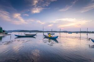 Traditional fishermen and boats in O Loan lagoon during sunset, Phu Yen province, Vietnam. Travel and landscape concept photo