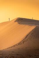 Aerial view of Vietnamese woman wearing ao dai dress across sand dunes in Ninh Thuan province, Vietnam. It is one of the most beautiful places in Vietnam photo