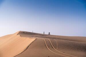 Aerial view of a peasant woman carries a bamboo frame on the shoulder across sand dunes in Ninh Thuan province, Vietnam. It is one of the most beautiful places in Vietnam photo