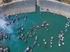 aéreo ver de loc un pescar aldea, vung tau ciudad. un pescar Puerto con tsunami proteccion hormigón bloques paisaje urbano y tradicional barcos en el mar. foto