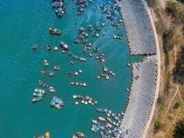 aéreo ver de loc un pescar aldea, vung tau ciudad. un pescar Puerto con tsunami proteccion hormigón bloques paisaje urbano y tradicional barcos en el mar. foto