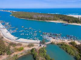 aéreo ver de loc un pescar aldea, vung tau ciudad. un pescar Puerto con tsunami proteccion hormigón bloques paisaje urbano y tradicional barcos en el mar. foto