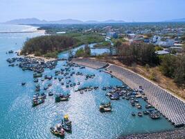 aéreo ver de loc un pescar aldea, vung tau ciudad. un pescar Puerto con tsunami proteccion hormigón bloques paisaje urbano y tradicional barcos en el mar. foto