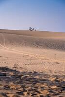 Aerial view of a peasant woman carries a bamboo frame on the shoulder across sand dunes in Ninh Thuan province, Vietnam. It is one of the most beautiful places in Vietnam photo