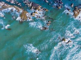 aéreo zumbido parte superior ver de hermosa olas estrellarse en el rocoso isla costa, Oceano olas y fantástico. Oceano en Vietnam. foto