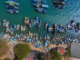 aéreo ver de loc un pescar aldea, vung tau ciudad. un pescar Puerto con tsunami proteccion hormigón bloques paisaje urbano y tradicional barcos en el mar. foto