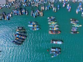 aéreo ver de loc un pescar aldea, vung tau ciudad. un pescar Puerto con tsunami proteccion hormigón bloques paisaje urbano y tradicional barcos en el mar. foto