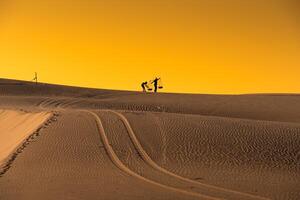 Aerial view of a peasant woman carries a bamboo frame on the shoulder across sand dunes in Ninh Thuan province, Vietnam. It is one of the most beautiful places in Vietnam photo