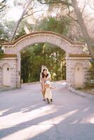 Laughing mother runs after a little girl along the park road at the gate photo