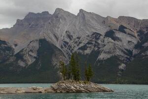 nublado día en rocoso isla en lago minnewanka, canadiense rocoso montañas, banff nacional parque foto