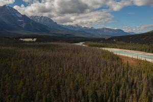 aéreo ver de el athabasca río con sus azulado color rodeado por miles de arboles y alto montañas de el canadiense Montañas Rocosas, en un otoño día en alberta, Canadá. foto