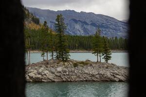 nublado día en rocoso isla en lago minnewanka, canadiense rocoso montañas, banff nacional parque foto