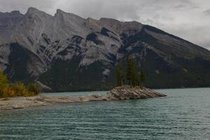 nublado día en rocoso isla en lago minnewanka, canadiense rocoso montañas, banff nacional parque foto