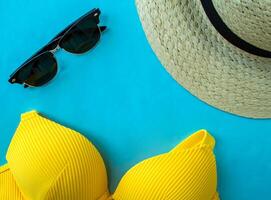 verano vacaciones. traje de baño, Gafas de sol y un sombrero en un azul antecedentes foto