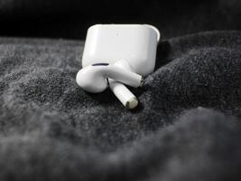 Closeup white TWS true wireless stereo earbuds in case isolated on black background. photo