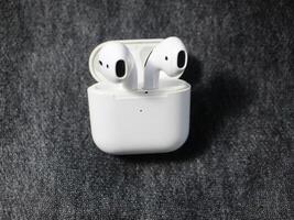 Closeup white TWS true wireless stereo earbuds in case isolated on black background. photo