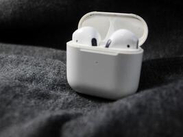 Closeup white TWS true wireless stereo earbuds in case isolated on black background. photo