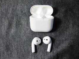 Closeup white TWS true wireless stereo earbuds in case isolated on black background. photo