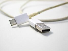 cerca arriba el blanco roto teléfono inteligente USB cable en blanco de madera antecedentes. foto