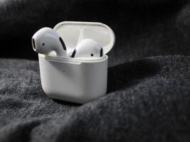 Closeup white TWS true wireless stereo earbuds in case isolated on black background. photo