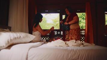 Due donne avendo un' conversazione nel un' accogliente Camera da letto con naturale luce. video